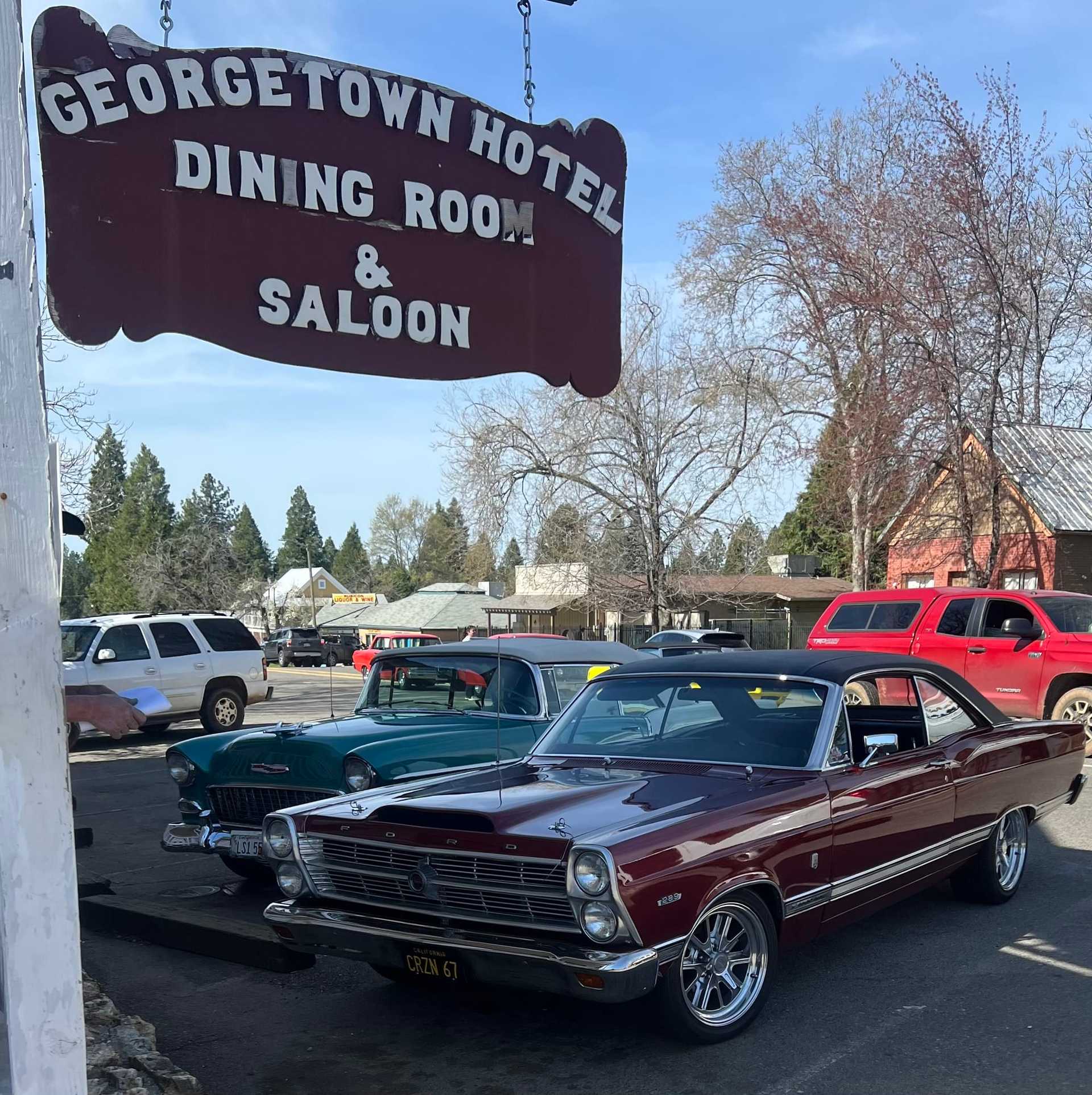 Classic cars parked at Georgetown Hotel with vintage sign overhead.