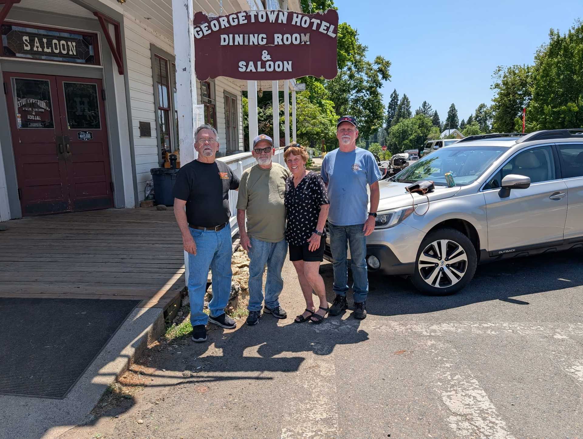 Group posing outside Georgetown Hotel & Saloon, sunny day.