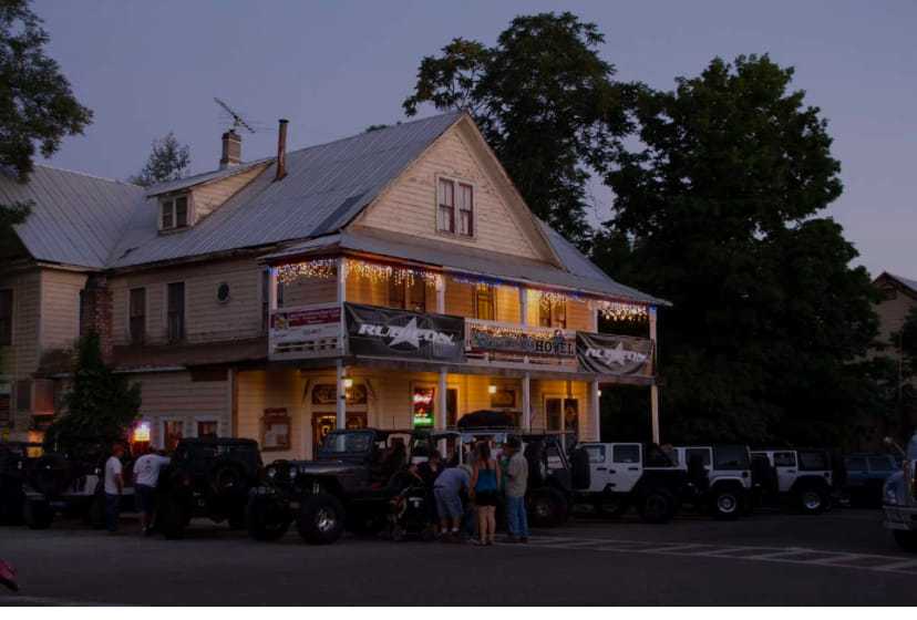 Historic building at dusk with parked Jeeps and people gathered outside.